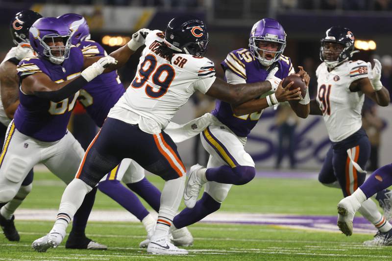Minnesota Vikings quarterback Joshua Dobbs (15) runs from Chicago Bears defensive tackle Gervon Dexter Sr. (99) during the first half of an NFL football game, Monday, Nov. 27, 2023, in Minneapolis. (AP Photo/Bruce Kluckhohn)