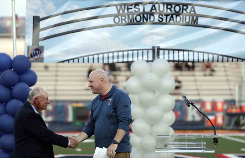 Neal Ormond III is greeted by SD129 School Board President Rich Kerns during a ceremony to name the stadium for the Ormond family Thursday September 15, 2022 in Aurora.