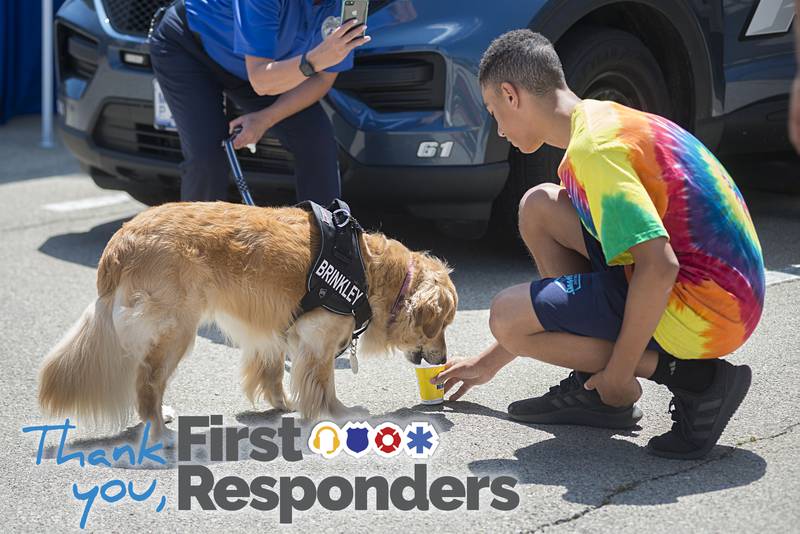 Isaiah Williams gifts Sterling Police mascot Brinkley a shaved ice with a dog treat from the Kona Ice truck at the Juneteenth celebration.