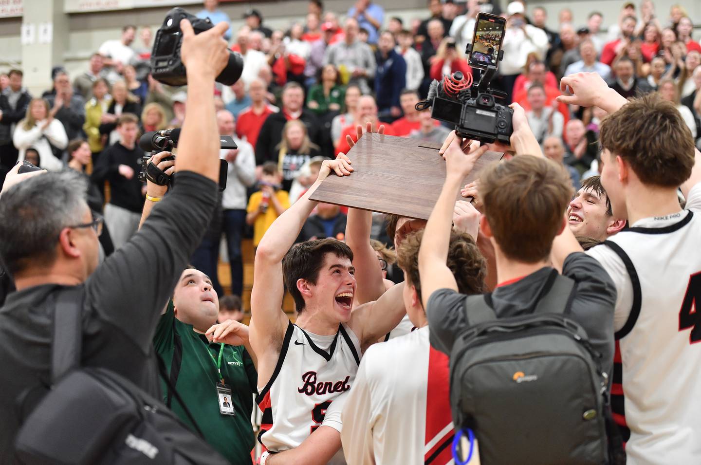 Benet’s Michael Doyle (middle) delivers the Class 4A Benet Sectional championship plaque to teammates after defeating Downers Grove North on March 7, 2025 at Benet Academy in Lisle.