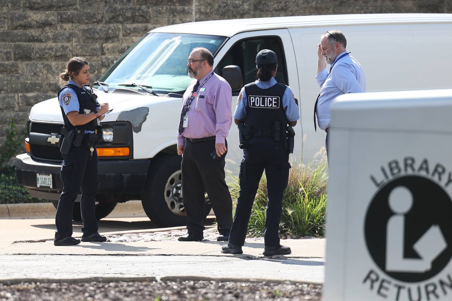 Managers of the Black Road Branch Library talk to the police after a bomb threat at that location on Thursday, Sept. 14, in Joliet.