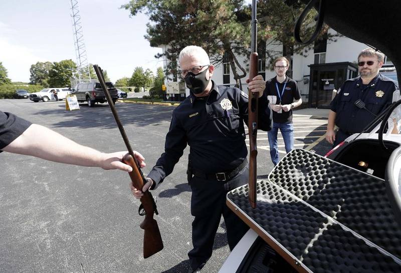 Kane County Undersheriff Patrick Gengler removes firearms from a vehicle during a community gun buyback event hosted by Sheriff Ron Hain Saturday in Aurora.