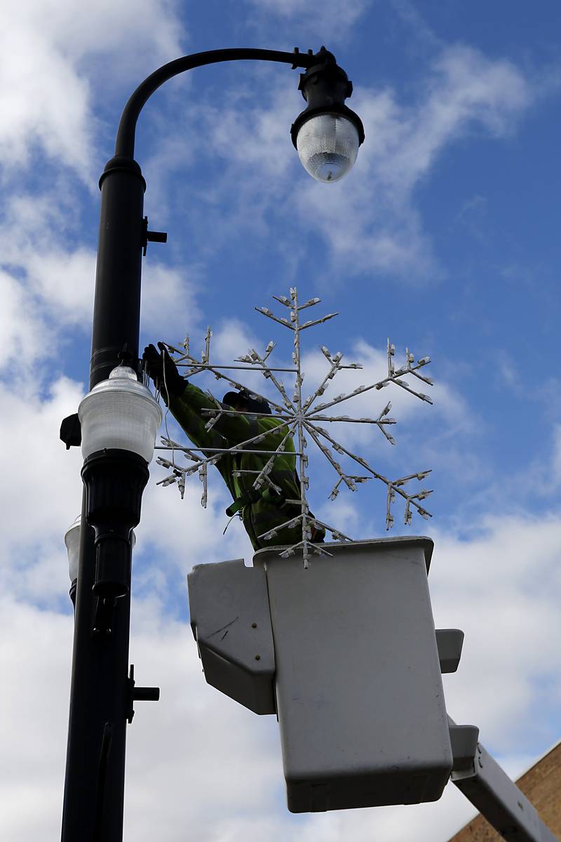A City of Woodstock employee installs a  snowflake decoration on Tuesday, Nov. 12, 2024, on the historic Woodstock Square. Workers are prepare the square for the city's annual Lighting of Woodstock Square event on Friday, Nov. 29.