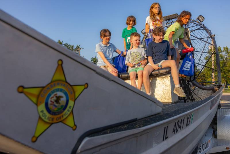 A group of kids listens to conservation officers explain how the specialty boat is used for rescue situations during National Night Out on Tuesday, Aug. 5, 2025, in Seneca.