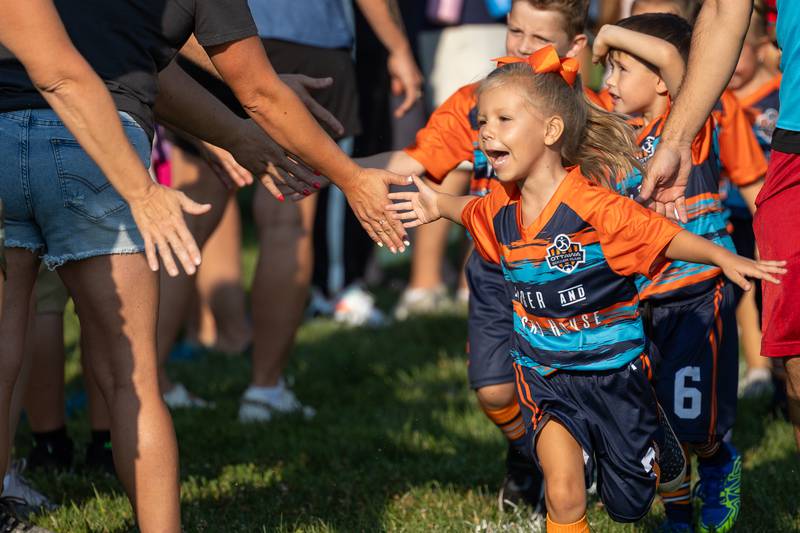 Ella Carmona high-fives friends and family attending the opening day ceremony of youth soccer on Saturday, Aug 16, 2025, at Peck Park in Ottawa.