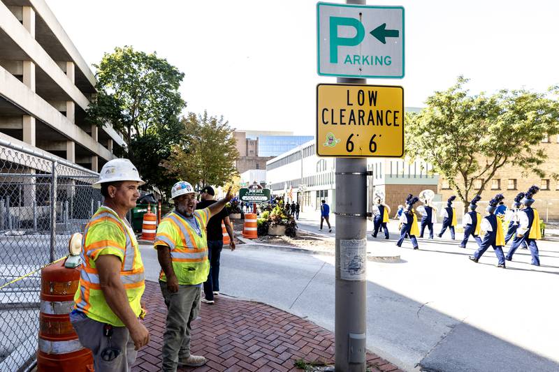 Construction workers take a break from working on the City Square project to wave to participants of the Joliet Central homecoming parade on Sept. 27. 2025.