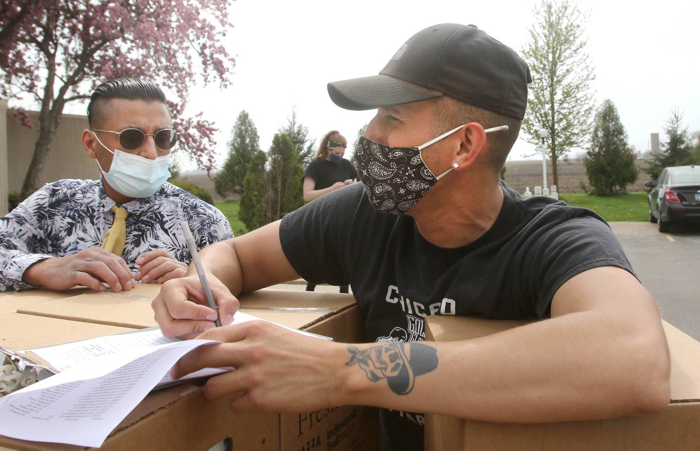 Elijah Saucedo, director of the Grow Mobile with DeKalb County Community Gardens, marks off names as they pick up their food during a distribution by DCCG Wednesday at Suburban Apartments in DeKalb.