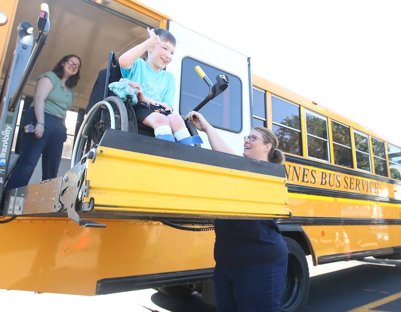 Cody a student at Lighted Way waves to the staff as he is helped down off of a school bus by Christina Croissant Johannes Bus Service director during the first day of school at the new Lighted Way building on Wednesday, Aug. 16, 2023 in La Salle.