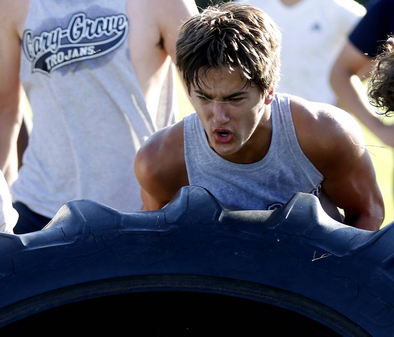 Cary-Grove’s Gavin Henriquez lifts a tractor tire during conditioning drills during summer football practice Thursday, June 30, 2022, at Cary-Grove High School in Cary.