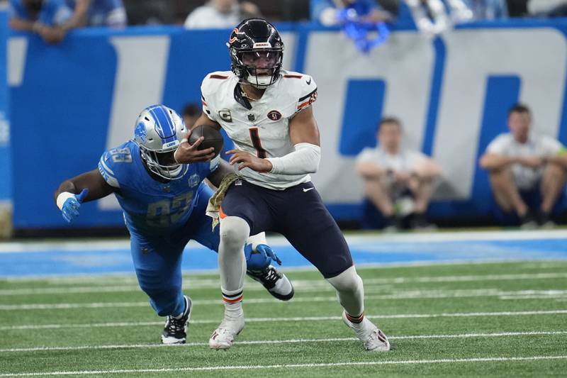 Chicago Bears quarterback Justin Fields is chased by Detroit Lions defensive end Josh Paschal during the second half, Sunday, Nov. 19, 2023, in Detroit.