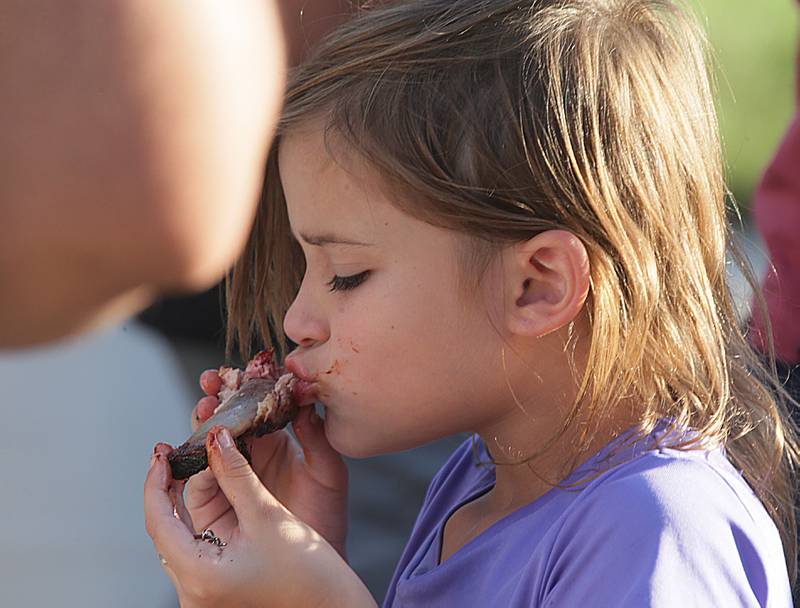 Audrena Tucker 6, of Princeton, sucks the BBQ juice off of a rib during the BBQ-n-Blues Festival on Friday, Sept. 9, 2022 in La Salle.