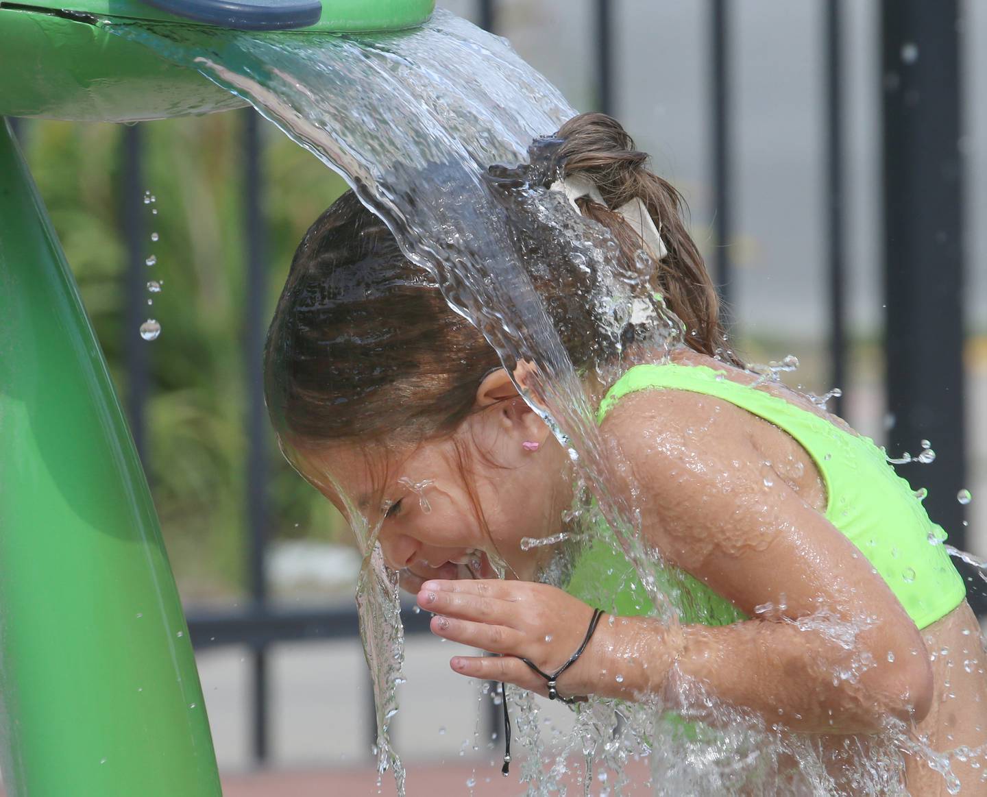 Josie Armstrong, of Streator, cools off underneath a fountain of water Monday, Aug. 21, 2023, at the Paul's Pad in Streator City Park. Temperatures will near triple digits Thursday as heat indexes are expected to exceed 110 degrees.