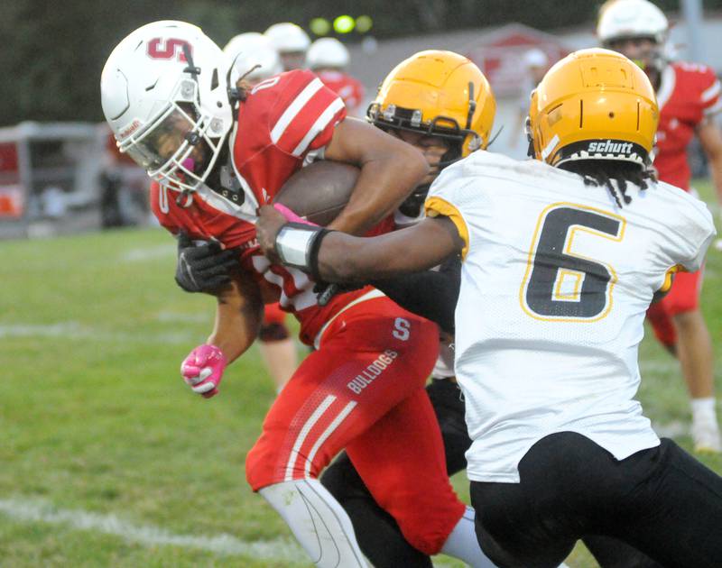 Streator's LA Moton (0) barrels ahead as Eisenhower's Mike Young and Garryon Henderson (6) try to bring him down Friday, Aug. 29, 2025, at Doug Dieken Stadium in Streator.