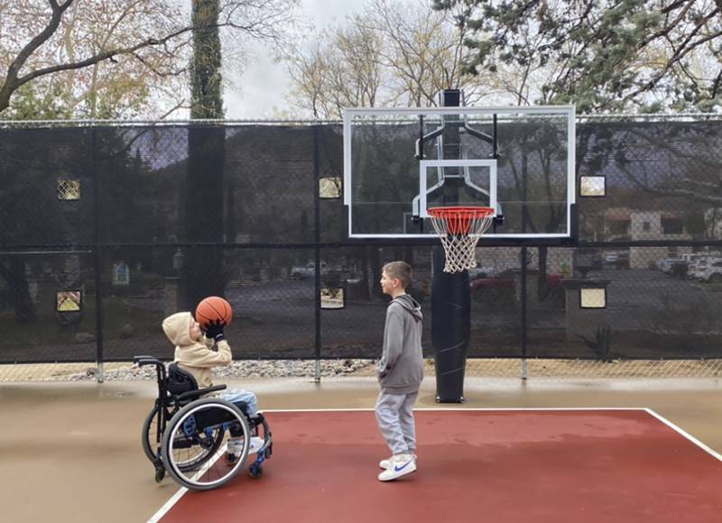 This undated photo provided by Jasculca Terman Strategic Communications shows twin brothers Cooper and Luke Roberts playing basketball. Cooper was a victim of the 2022 Fourth of July parade shooting in Highland Park and remains paralyzed from the waist down.