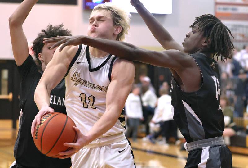 Sycamore's Burke Gautcher tries to get between Kaneland's Evan Frieders (left) and Kaneland's Freddy Hassan on his way to the basket during their game Friday, Feb. 10, 2023, at Sycamore High School.