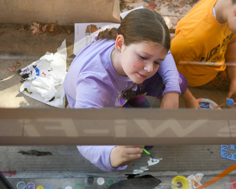 kiara Evola, 9 years old, of Downers Grove paints a window during the Halloween Window painting event held Downtown Downers Grove on Saturday Oct. 21, 2023.
