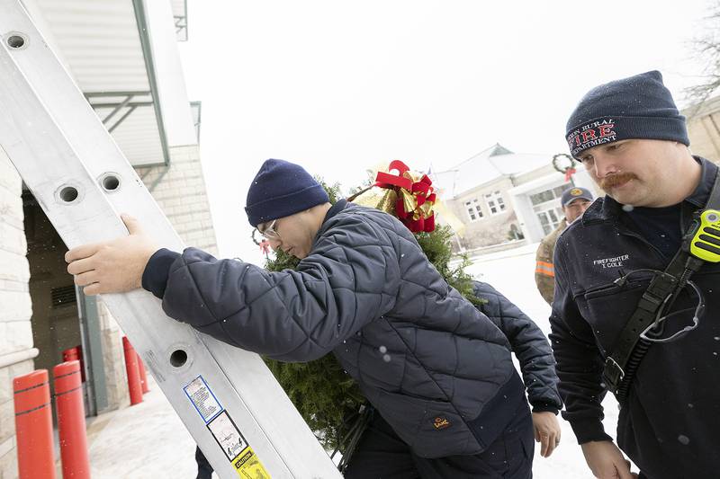 Dixon firefighter Tristan Ramirez climbs a ladder to put up the department’s wreath Monday, Dec. 2, 2024. Keep the Wreath Red is a program meant to remind people of the extra dangers of fire hazards during the holiday season. A red light on the wreath will remain lit unless a holiday related fire occurs.