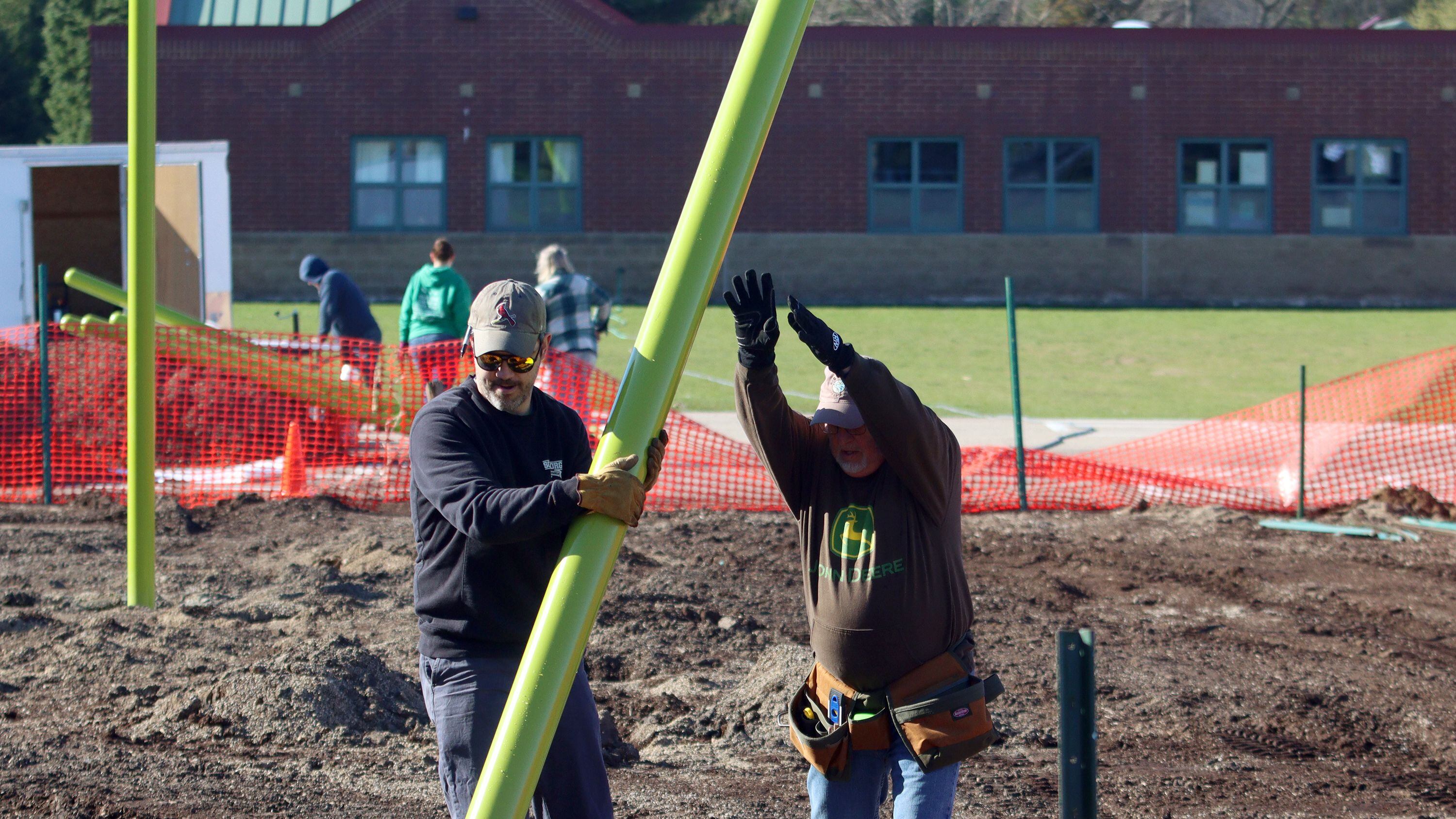 Joe Weaver, left, and Denny Nielsen place a pole as volunteers and friends of Three Oaks Elementary School constructed a new playground at the Cary school on Saturday.