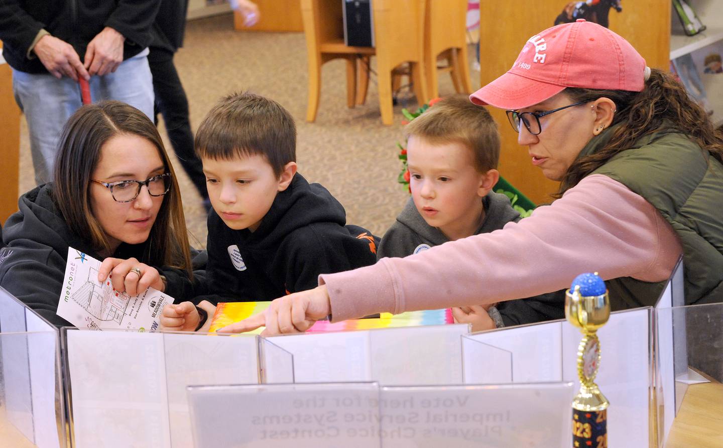 Carter Morel, 7 and his brother Stetson, 4 with their mom Darian (left) and Grammy Jennifer Kleinwachter, vote for their favorite hole during the Friends of the Yorkville Library's annual Mini Golf FUN Raiser on Sunday Feb. 5, 2023.