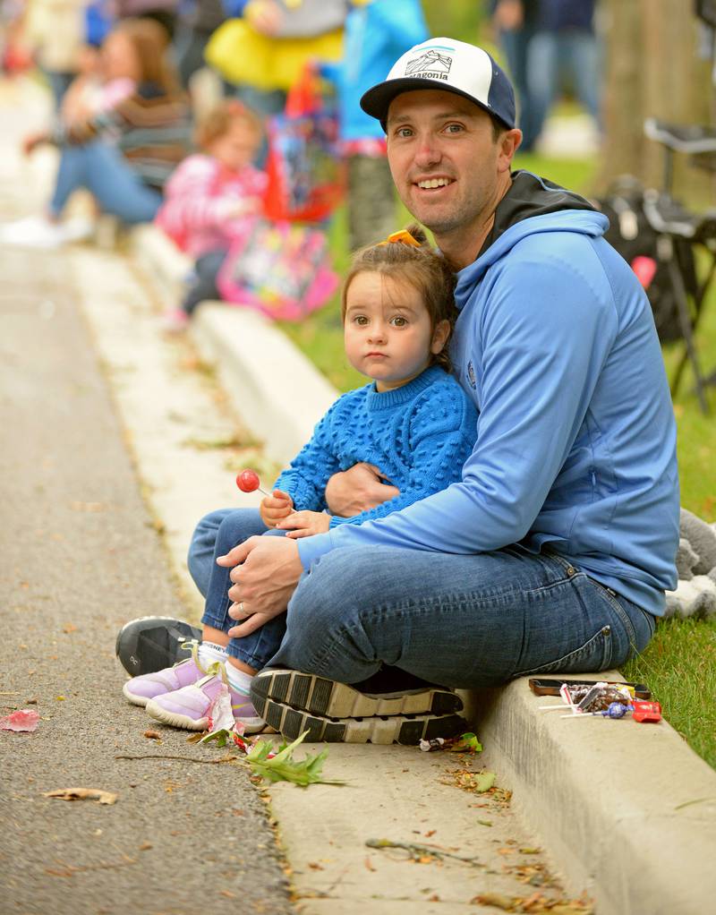 Lilly Powers, 3 of La Grange, sits on her dad, Rob’s lap watching the Lyons Township High School homecoming parade on Saturday, Sept. 24, 2022.
