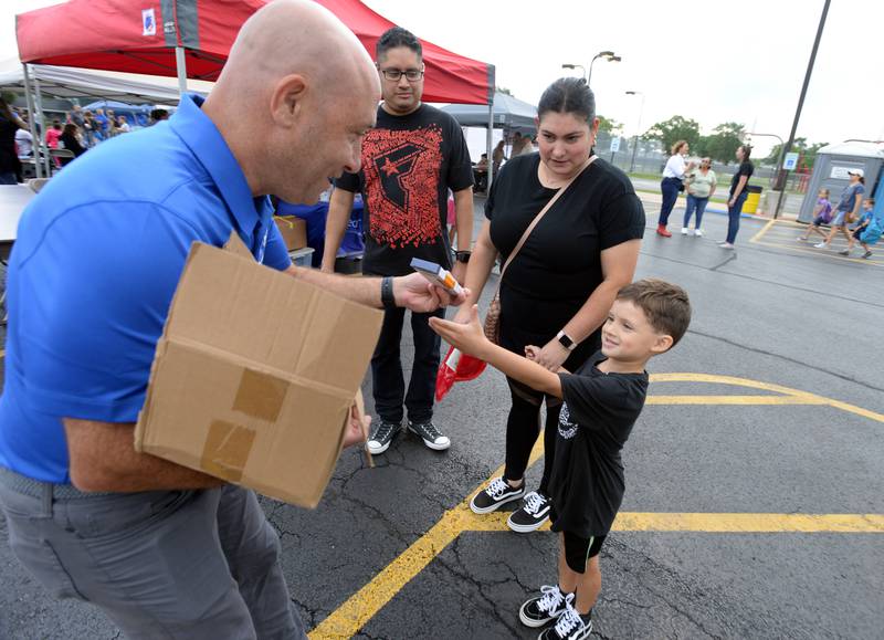 District 105 Superintendent Brian Ganan hands out pencils to students including 1st grader of Ideal, Landon Soto of Countryside (alongside his parents Rene and Dali) attending the Back to School/Neighborhood Fest held at Ideal Park Saturday Aug 20, 2022.