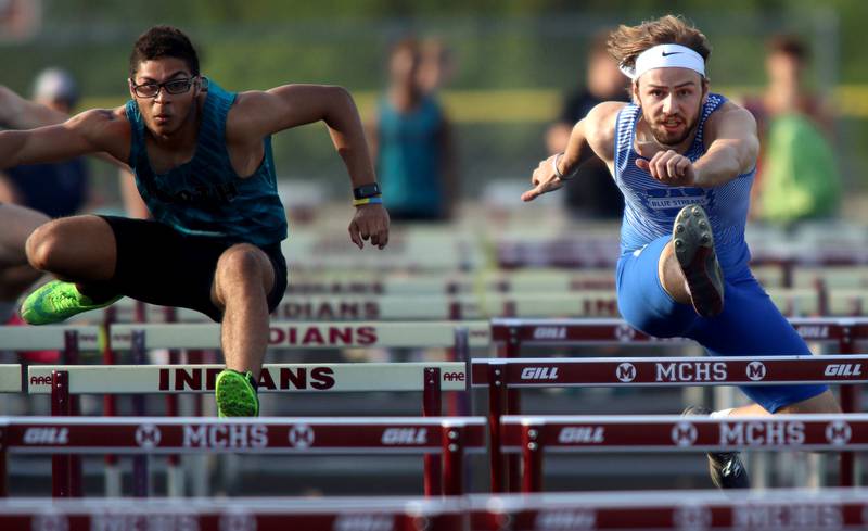 Woodstock North’s Giovanni Young, left, and Woodstock’s Jared Kniola, right, race in the 110-meter high hurdles during Kishwaukee River Conference track meet action at Marengo Tuesday night.
