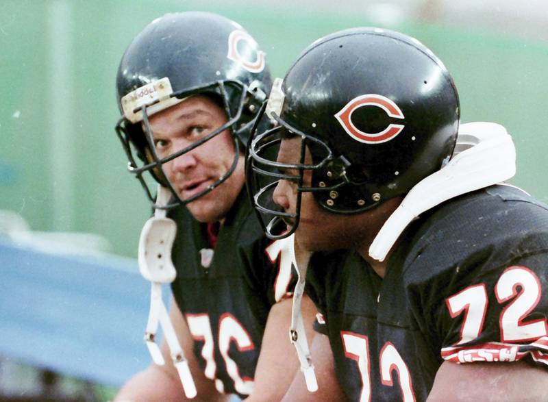 Chicago Bears defensive lineman Steve McMichael looks at the camera while sitting the bench with teammate and defensive lineman William Perry "The Refrigerator" during a game in 1992.
