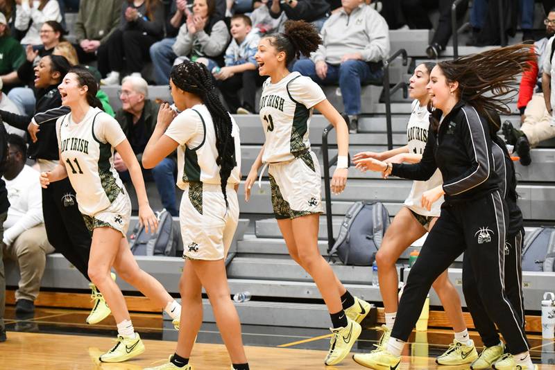 Bishop McNamara's Trinitee Thompson, center, rejoices with teammates as the Fightin' Irish secured a 51-30 victory over Seneca in the IHSA Class 2A Herscher sectional semifinal Tuesday, Feb. 25.