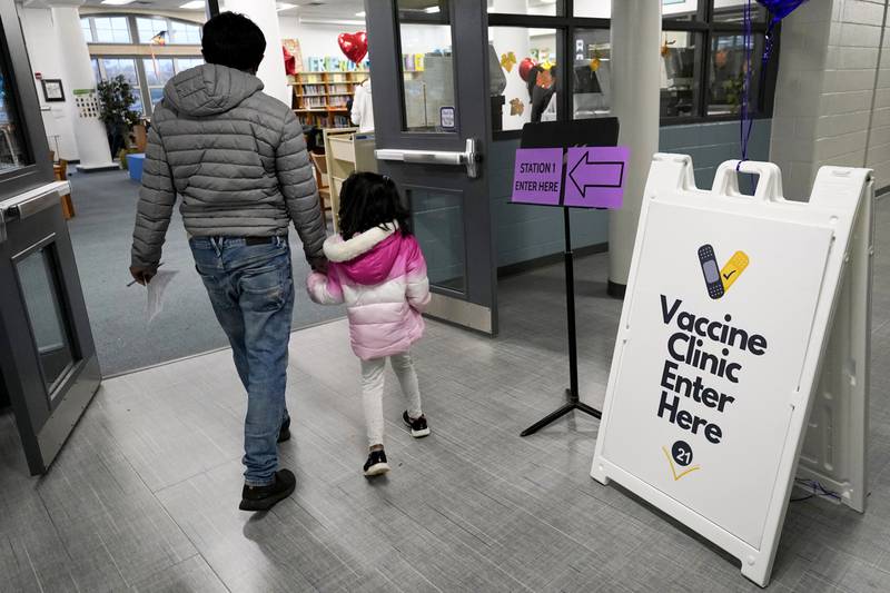 An information sign is displayed as a child arrives with her parent to receive the Pfizer COVID-19 vaccine for children 5 to 11-years-old at London Middle School in Wheeling, Ill., Wednesday, Nov. 17, 2021.