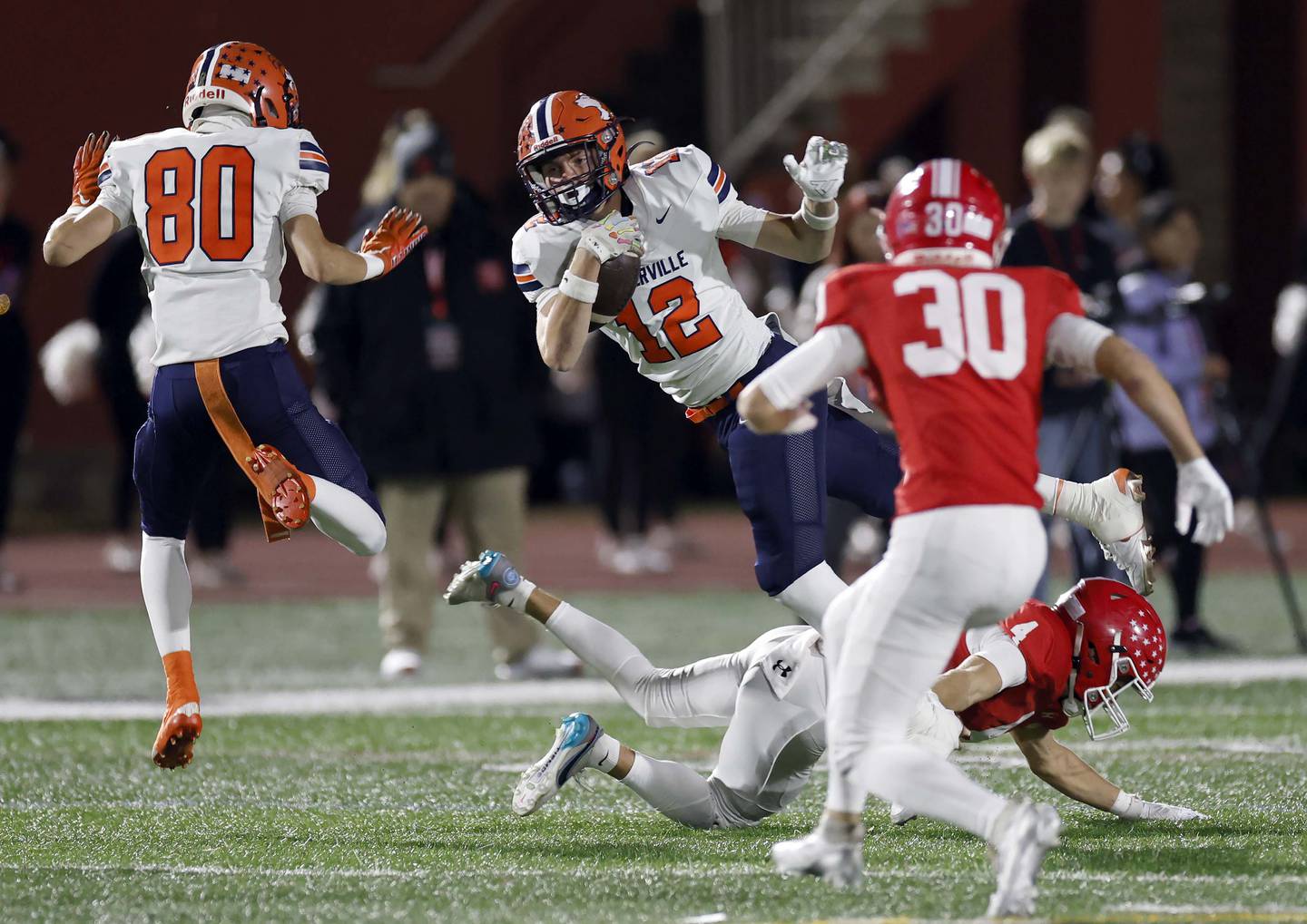 Naperville North's Jack Zitko (12) leaps for more yards past Naperville Central's Gavin Ellison (4) Friday, Oct. 24, 2025 at North Central College in Naperville.