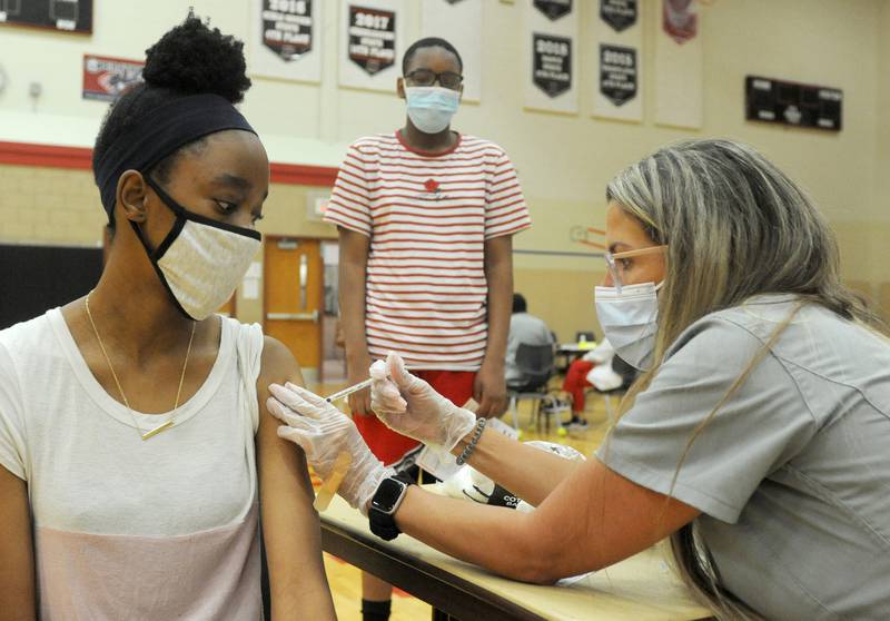 Rosie Muteba, 13,  of Huntley, receives a dose of the Pfizer Covid Vaccine from pharmacist assistant Jacquelyn Potokar   as her brother, Sael, 14, waits for his shot Saturday morning, July 31, 2021, during a Walgreen’s Vaccination Clinic at Huntley High School.