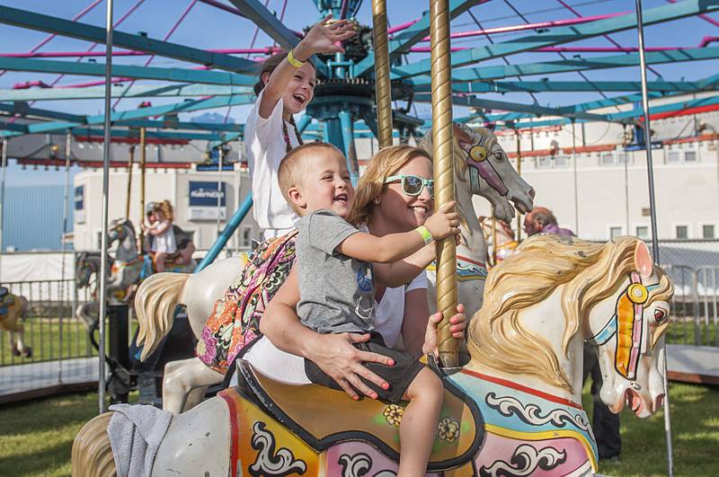 Theo Kness, 3, mom Stacy Kness and friend Charlee Shoemaker wave from the merry-go-round during the opening day of Dixon’s Petunia Fest carnival on Thursday, June 30, 2022.