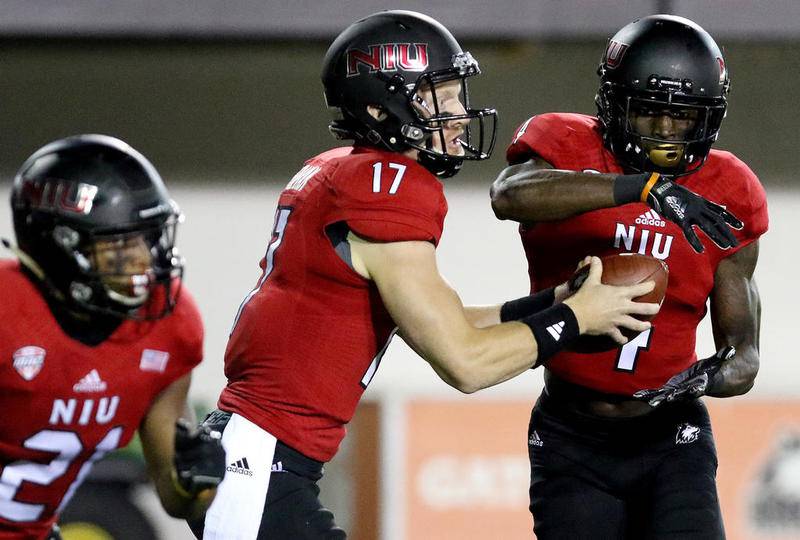 Northern Illinois University quarterback Ryan Graham hands the ball off to Christian Blake during its home opener against Boston College on Friday at Huskie Stadium.