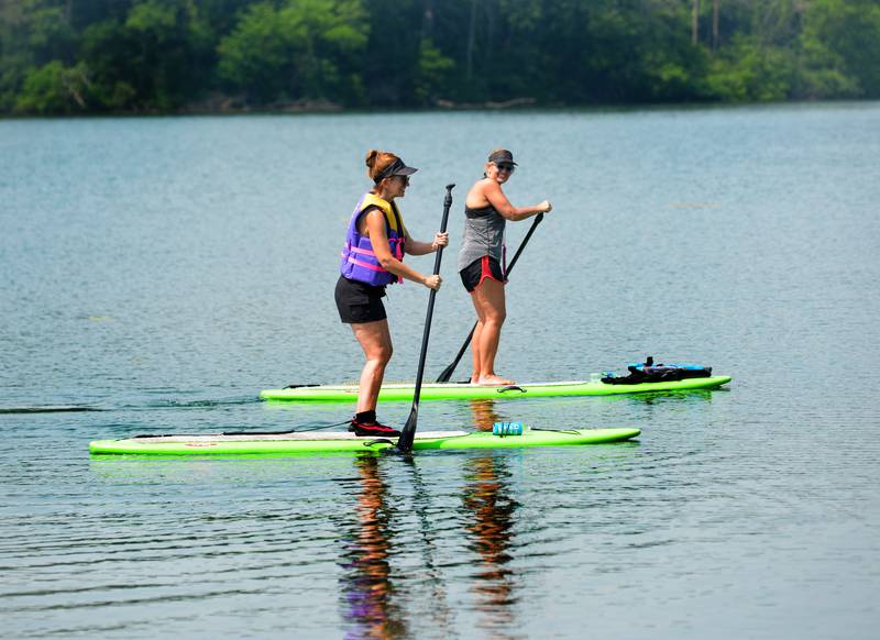 Jenny McClary of Fulton (left) steadies herself on her first adventure of stand-up paddleboarding while getting tips from her big sister, Lori Cavanaugh of Clinton, Iowa, on Lake Carlton in Morrison-Rockwood State Park on Sunday, June 4. Sunday's sunny skies and warm temperatures made for a perfect day on the lake.