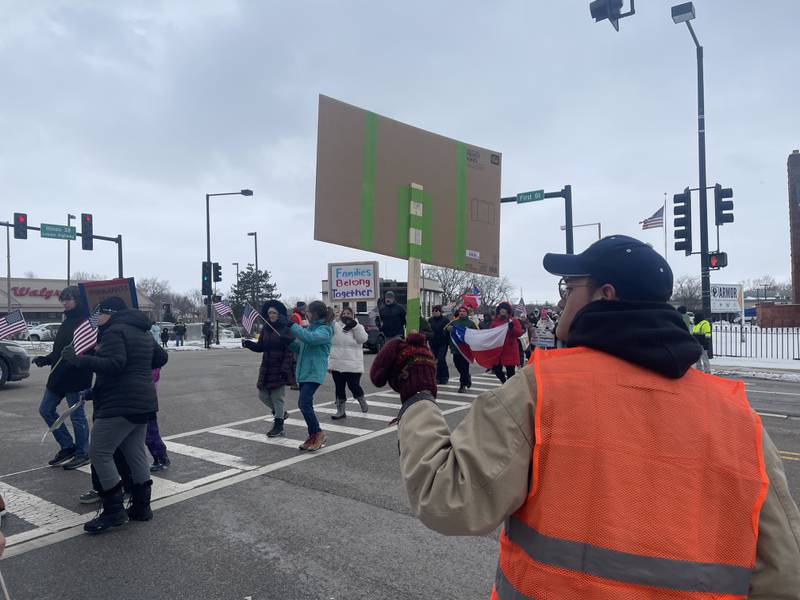 Demonstrators make their way across the Lincoln Highway toward Peace Corner in DeKalb Sunday, Feb. 16, 2025, where they gather for a rally featuring remarks by several speakers.