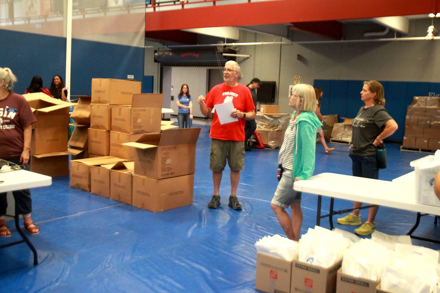 Volunteer Rick Green (center) directs some of the other volunteers as part of Project Backpack at Elgin Community College. Over 1,500 backpacks will be distributed to area students in need.