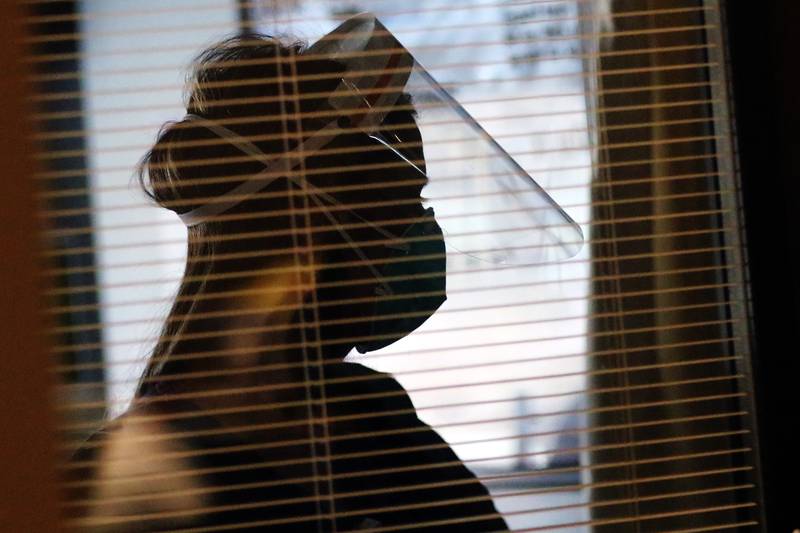 Occupational therapist Jagruti Patel is seen silhouetted, wearing a face shield and face mask inside a COVID-19 patient's room at Northwestern Medicine Huntley Campus on Thursday, March 4, 2021 in Huntley.