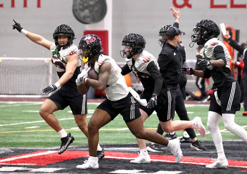 Northern Illinois defensive players celebrate after an interception during the first spring football practice Thursday, March 27, 2025, in the Chessick Practice Center at NIU in DeKalb.