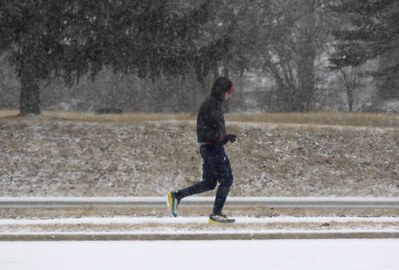 A man runs along Walkup Road near Veteran Acres Park on Wednesday, Feb. 12, 2025, in Crystal Lake as a winter storm starts to bring heavy snow to the McHenry County area