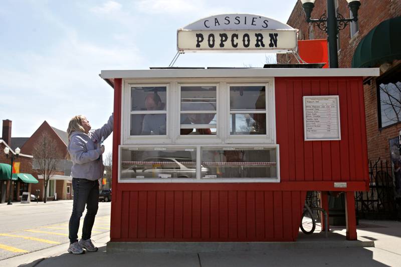 Shaw Local 2013 file photo – Cassie Oltman (left) cleans the windows of Cassie's Popcorn Stand while her husband, Troy, paints the interior as the two prepare to open for the season this coming Sunday. The stand will celebrate 100 years of operation in July 2024.