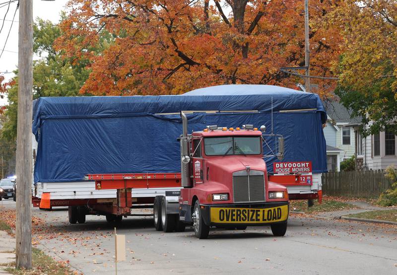A house is carried on a truck Tuesday, Oct. 22, 2024, down Pleasant Street in DeKalb. The home was moved from the DeKalb County History Center property in Sycamore to its new location on Pleasant Street by Devooght House Movers and Habitat For Humanity for Heaven Allen and her son who will be living in the home when it is completed.
