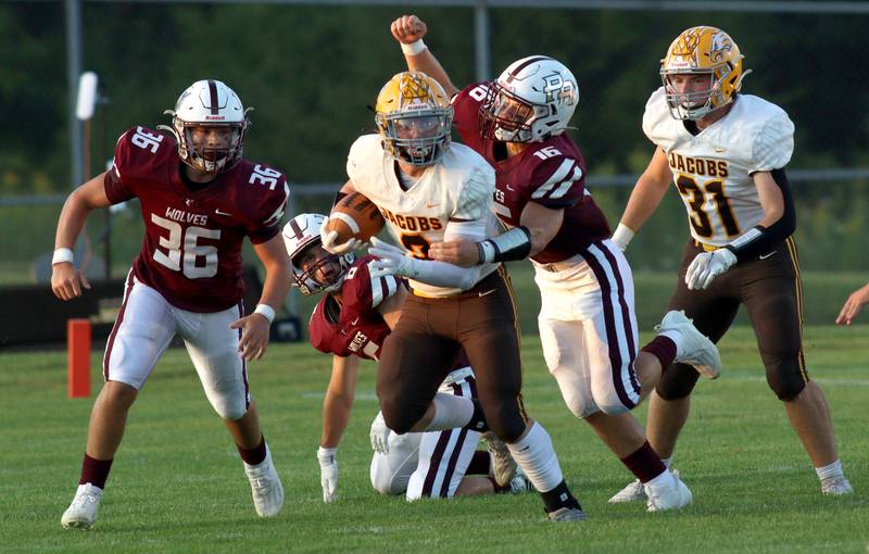 Jacobs’ Caden DuMelle runs the ball as Prairie Ridge’s Dominic Creatore, right, moves in for a tackle in varsity football at Crystal Lake Friday night. Prairie Ridge won 6-0.