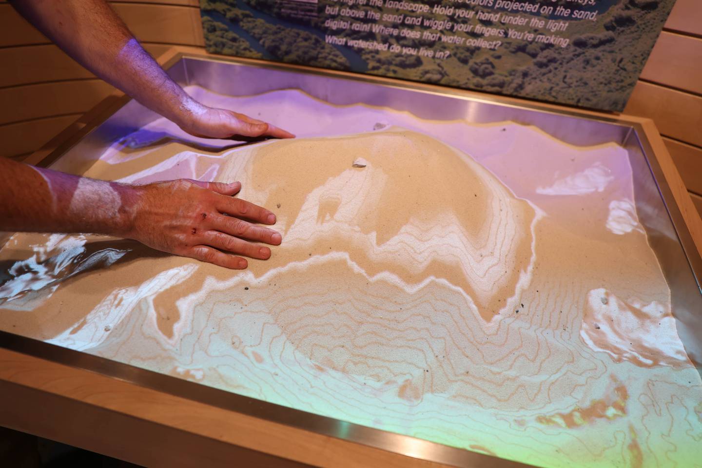 Jerome Gabriel Four Rivers Environmental Center Facility Supervisor creates topography models by shaping sand at the new augmented reality sandbox. Tuesday, Sept. 20, 2022, in Channahon.