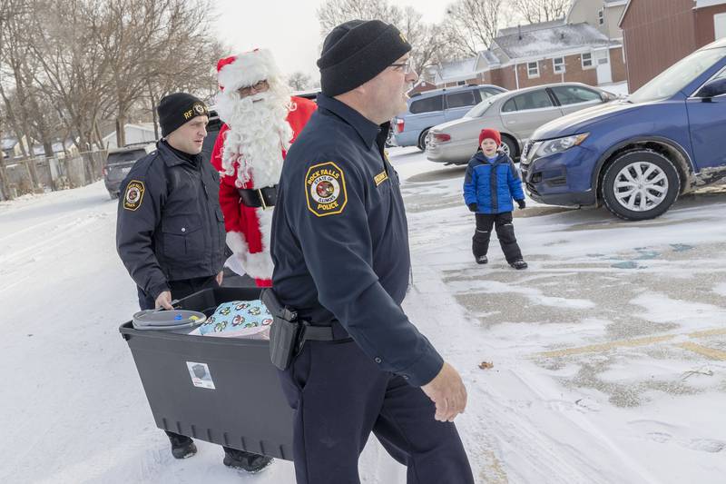 Chief Dave Pilgrim (right) and officer Zach Lyerla carry a bin of items into a home Saturday, Dec. 24, 2022 in Rock Falls. Through the generous donations of the community, the department raised $4400 to help out five families in Rock Falls.