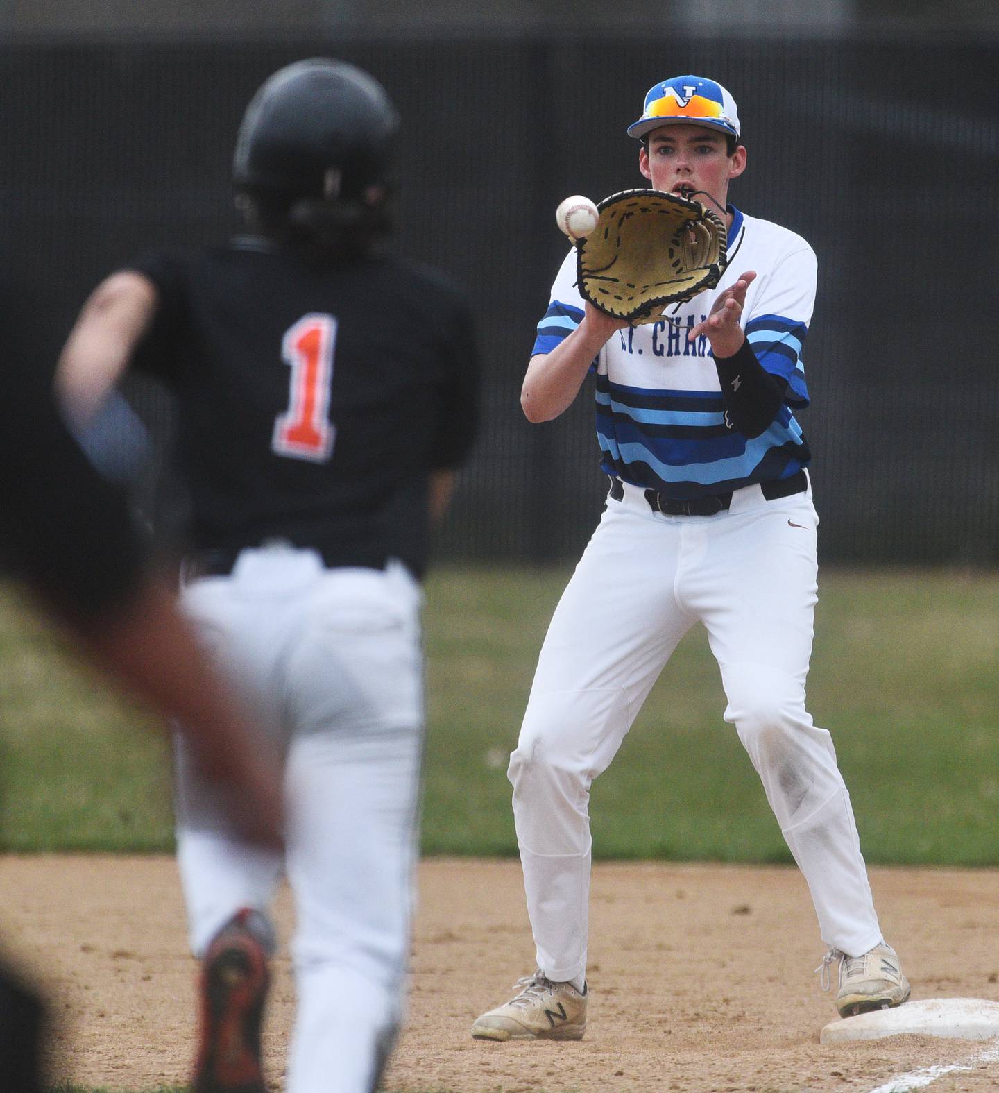 St. Charles North's Colin Ryder takes the throw from the catcher to get Wheaton Warrenville South's Jon Jensen out at first base during Tuesday's baseball game in St. Charles.