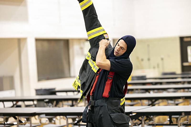 Dixon City firefighter Tyler Hansler pulls on his gear Thursday, Oct. 12, 2023 during a demonstration for Fire Prevention Week at Jefferson School.