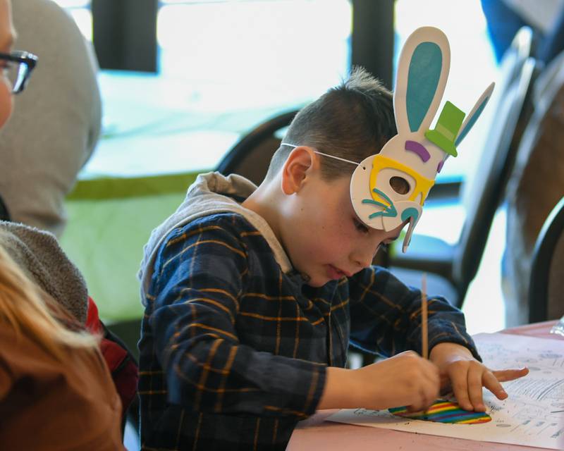 Jordan Schneider, 8, of Rochelle, wears a bunny mask that he made and scratches a paper Easter egg to reveal the colors during the DeKalb Park District's annual Breakfast with the Bunny on Saturday, March, 23, 2024, held at Hopkins Park, 1403 Sycamore Road in DeKalb.