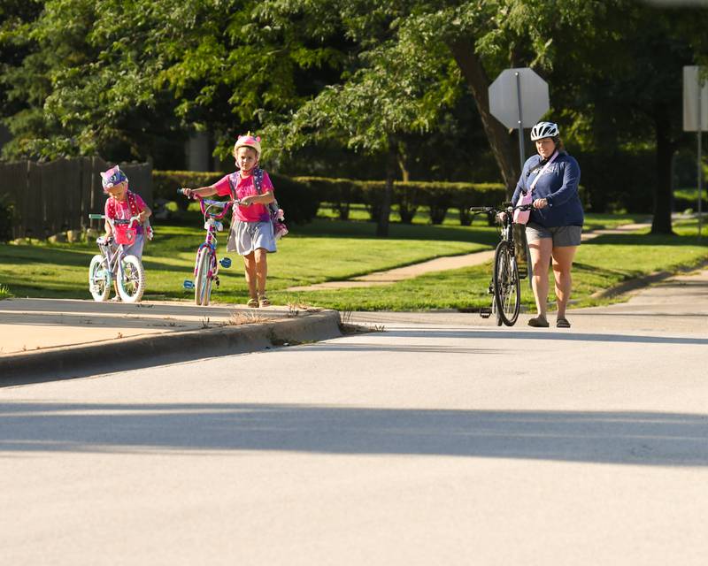 Sisters Layla, 5, and Emilia Placek, 7, walk their bikes to the bike rack with their mom Caitlin Placek on Wednesday Aug 16, 2023, during the first day of school at Fox chase Elementary in Oswego.