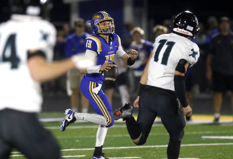 Johnsburg's Carter Block scrambles as he looks to pass while being chased by Woodstock North's George Kingos during a Kishwaukee River Conference football game on Friday, Sept. 26, 2025, at Johnsburg High School.