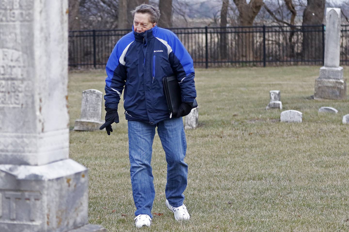 Doug Peterson, of McHenry, searches through Ostend Cemetery to find an unmarked burial plot on Tuesday, Dec. 21, 2021, in McHenry.  Peterson and Amanda Helma are working to identify the boy who died in 1963 and issue a headstone for him.